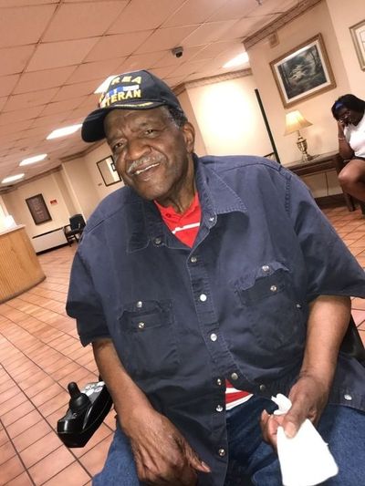 Raymond Armstead, sitting in a power chair, wearing a "Korean War Veteran" hat.
